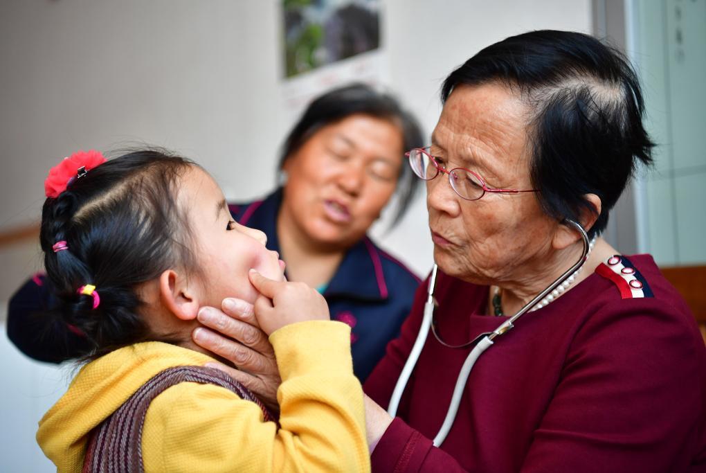 2018年4月29日，路生梅（右一）在家中給一名小朋友看病。新華社記者 邵瑞 攝